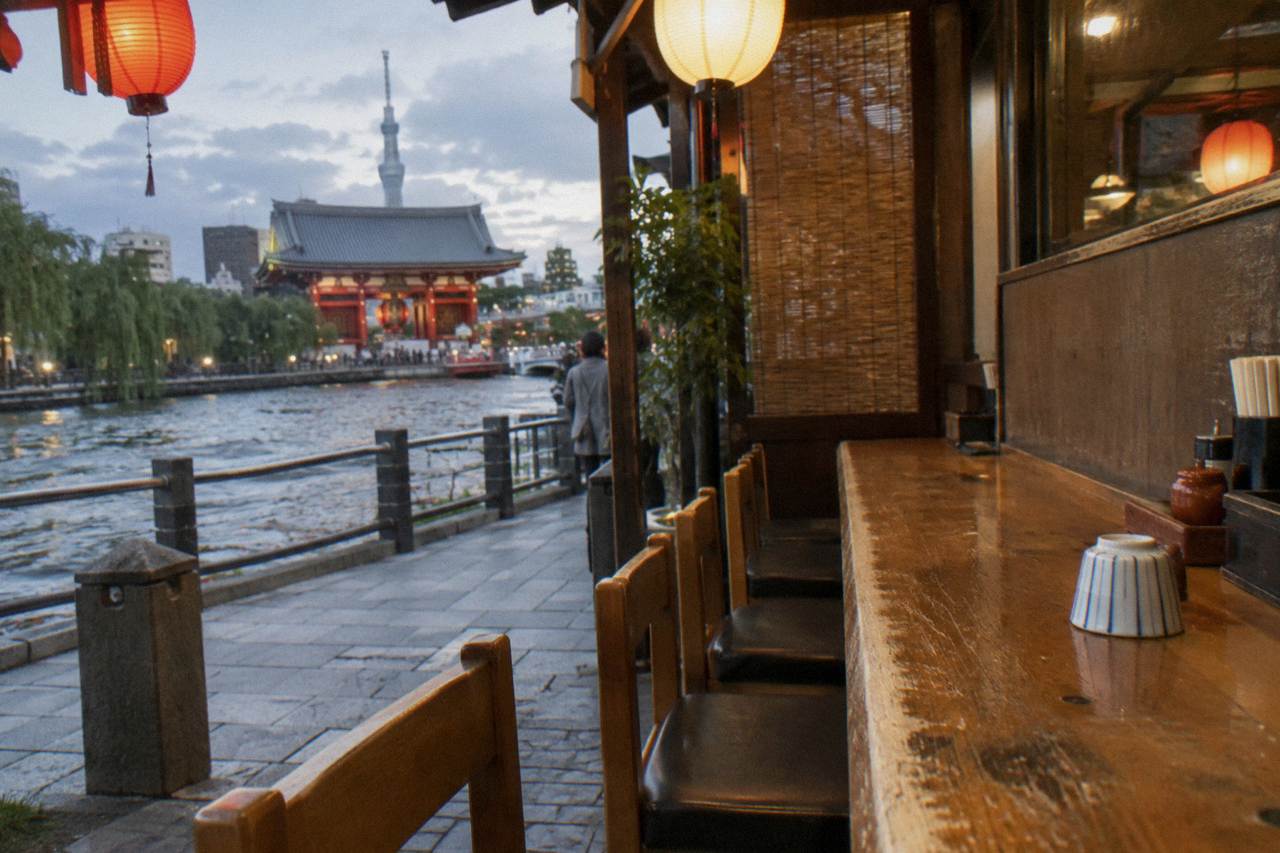 Quiet wooden counter of a small Tokyo restaurant with paper lanterns glowing in the evening