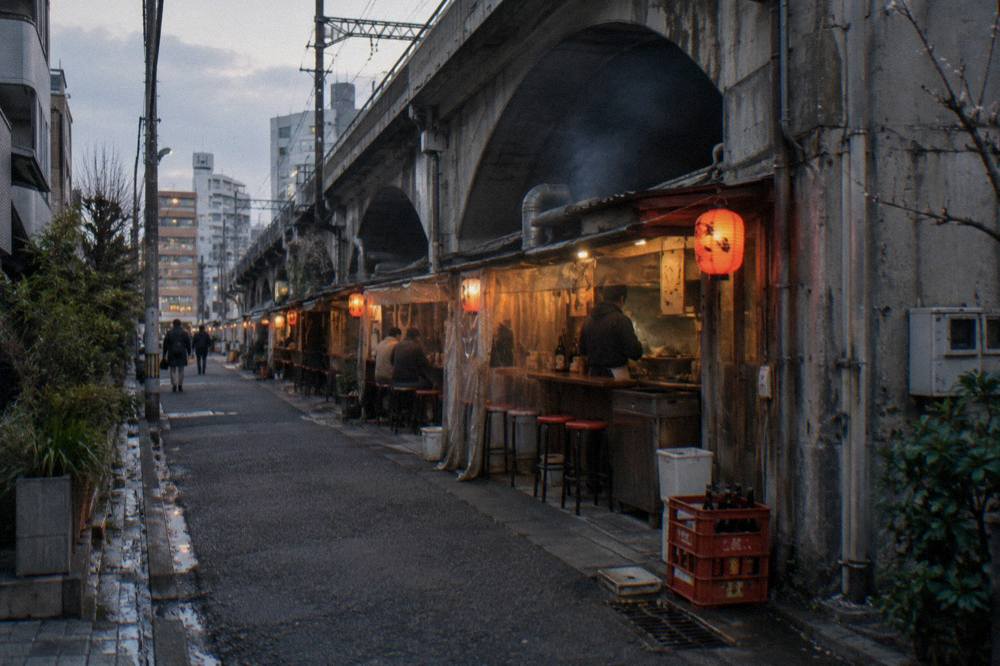 Row of small grill counters in a narrow lantern-lit alley at dusk