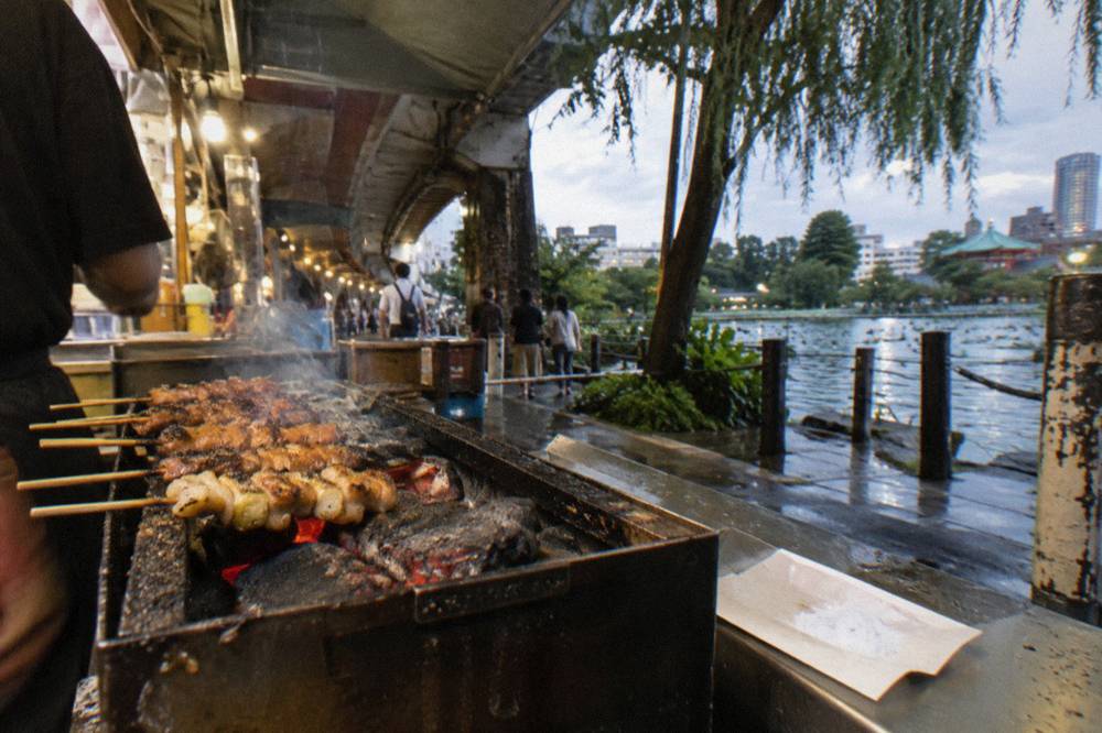 Close-up of skewers grilling over charcoal at a small counter