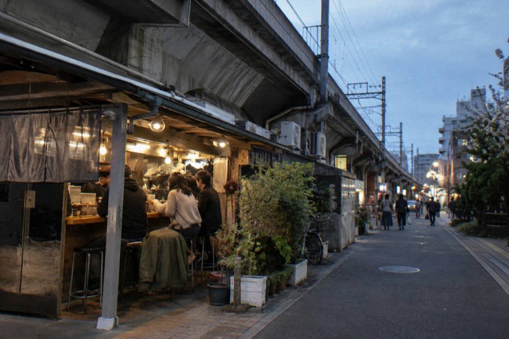 Small-group food tour standing at a bright stall counter on a shopping arcade street