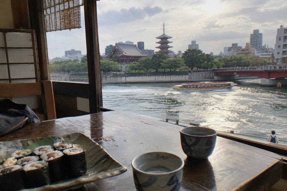 Small cups of sake and a plate of freshly rolled maki on a wooden class table