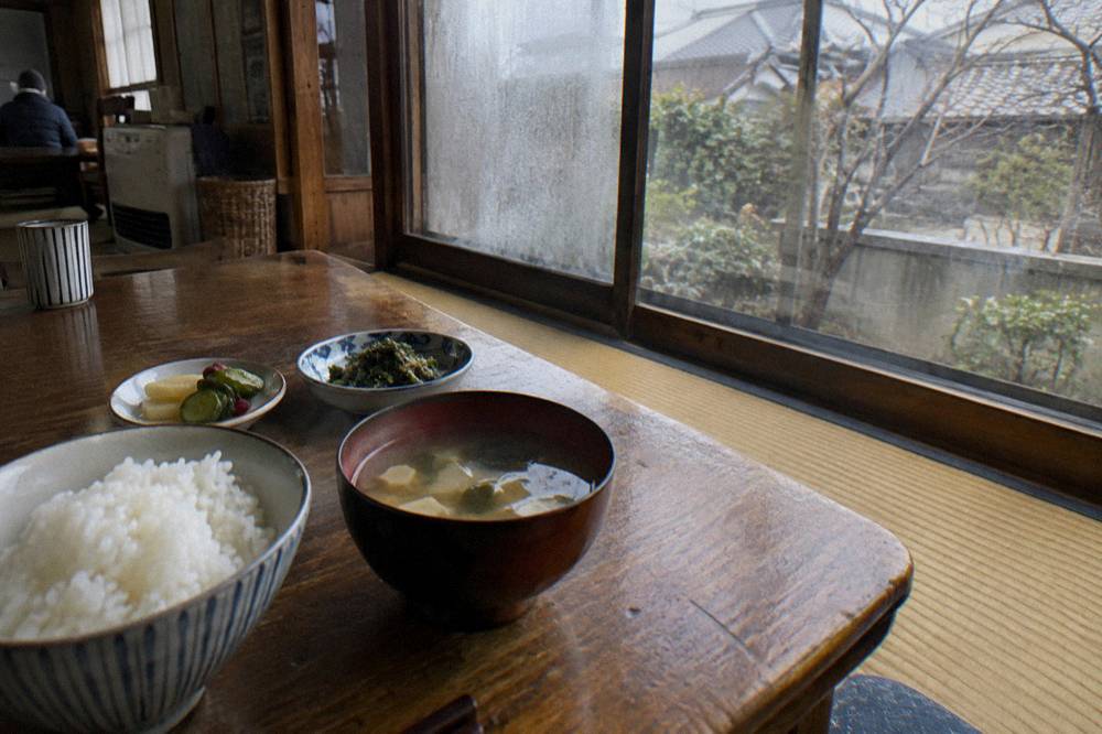 Cooked Japanese dishes including rice, soup and sides arranged on a classroom table