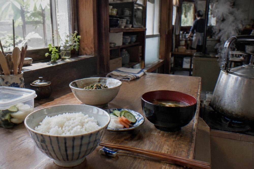 Home kitchen counter laid out with prepared dishes, rice and chopsticks