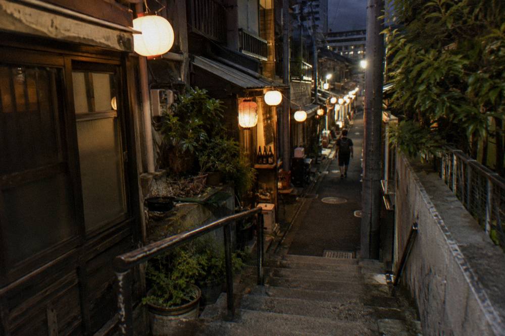 Narrow lantern-lit alley of small bars and restaurants at night