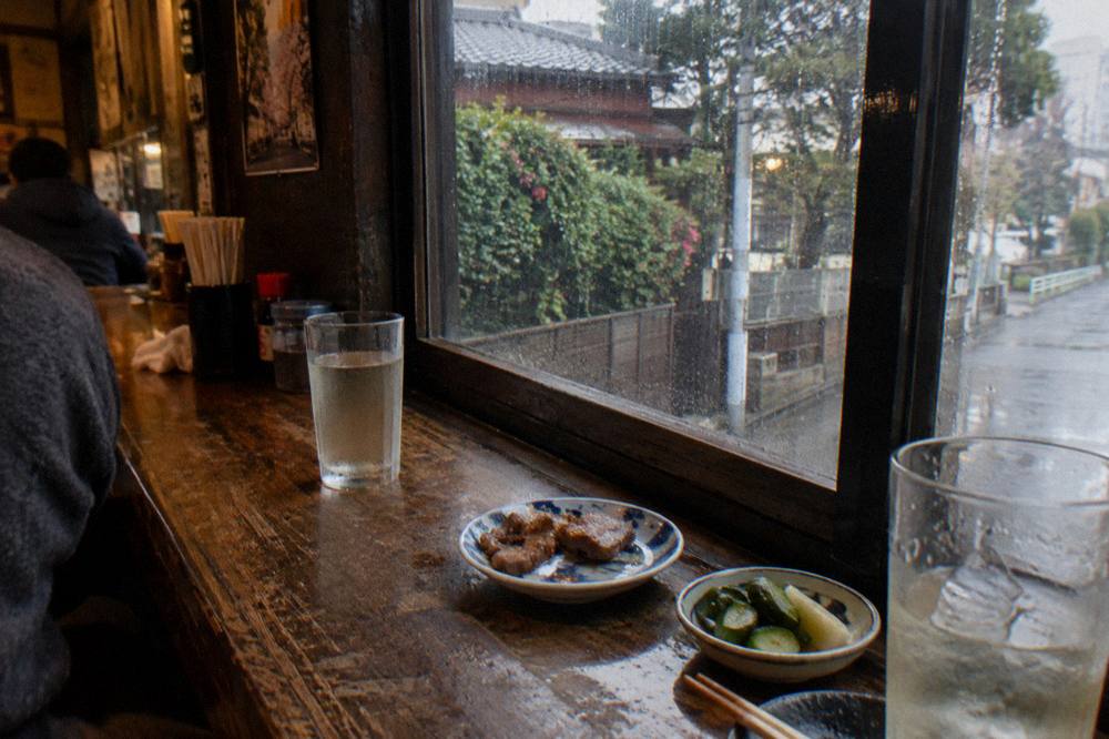Small plates and drinks arranged along a wooden counter in a small restaurant