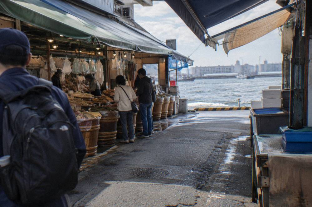 Guide leading a small group between market stalls in Tsukiji