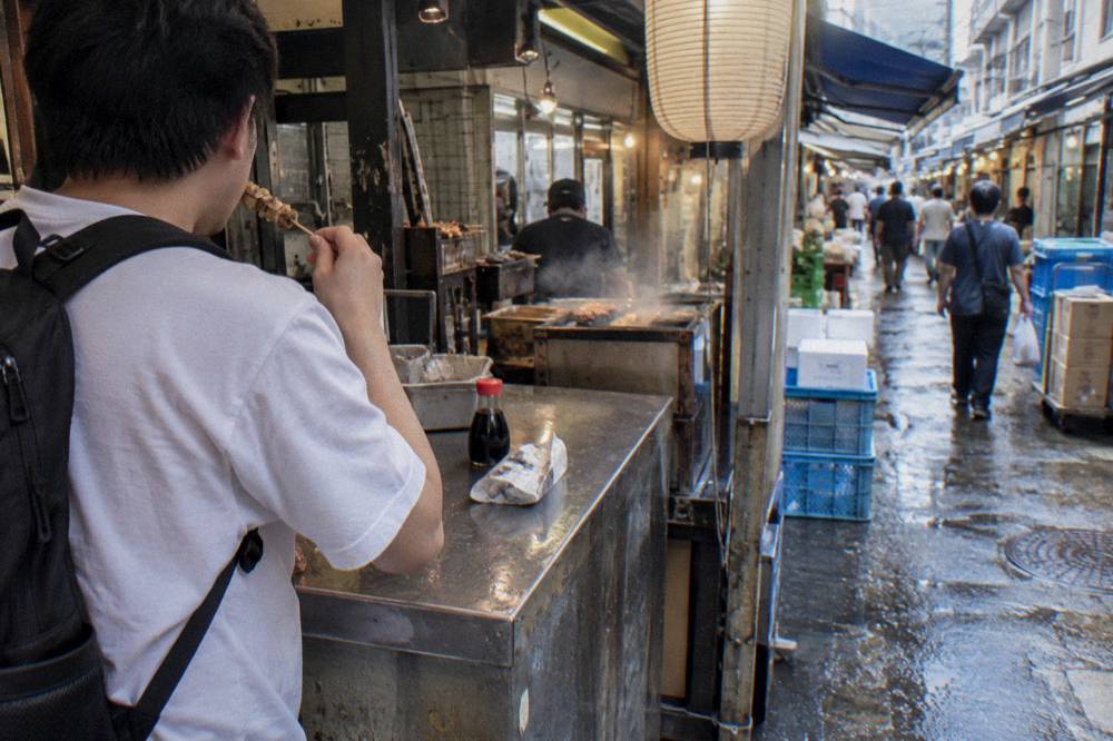 Customer eating a snack standing at a Tsukiji stall counter