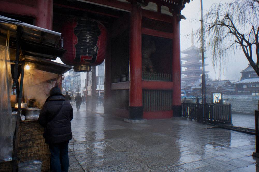 Steam rising from a food stall counter beside a shrine gate entrance in an old district
