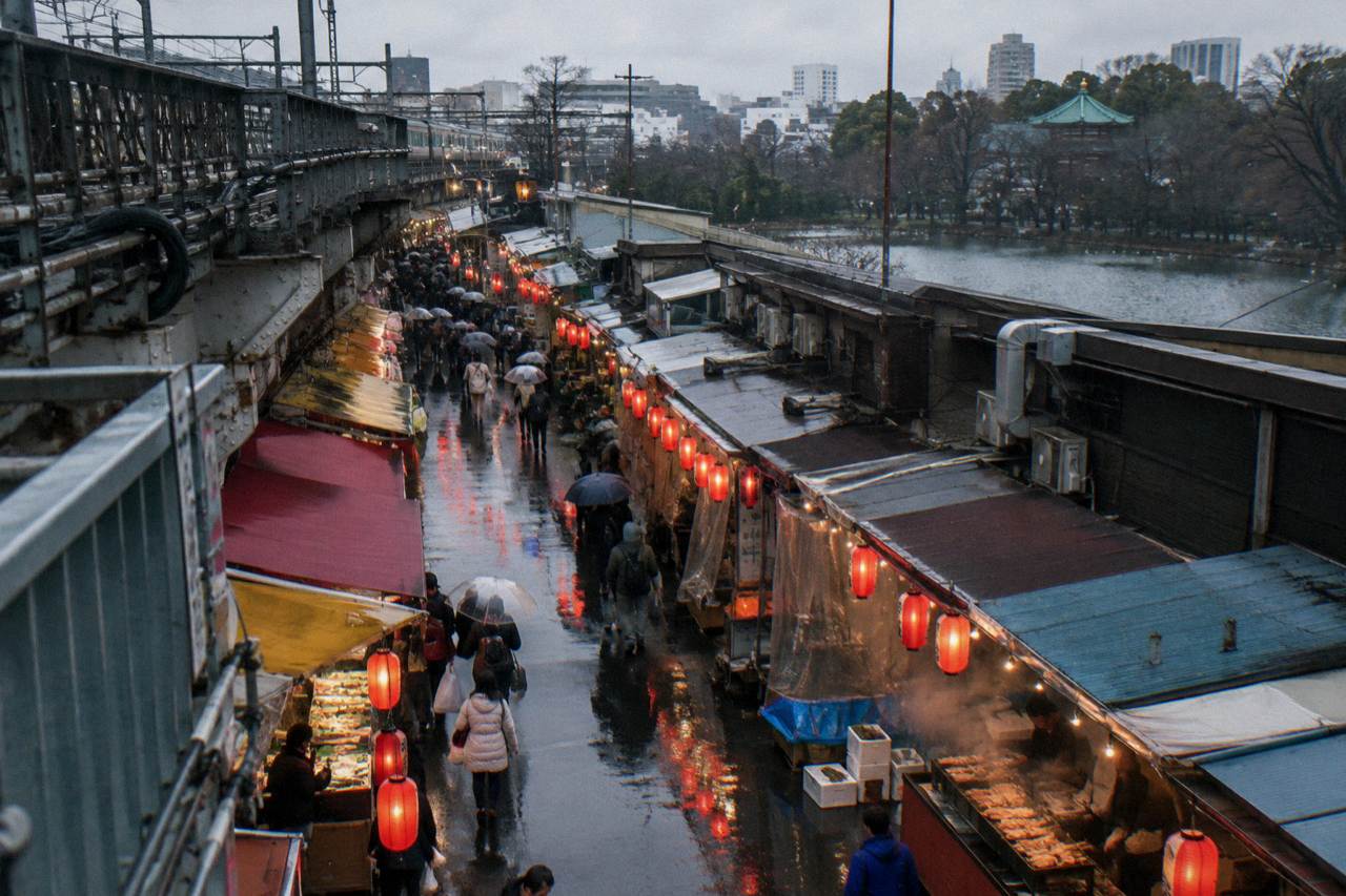 Lantern lit row of food stalls along a narrow market street in Ueno at dusk