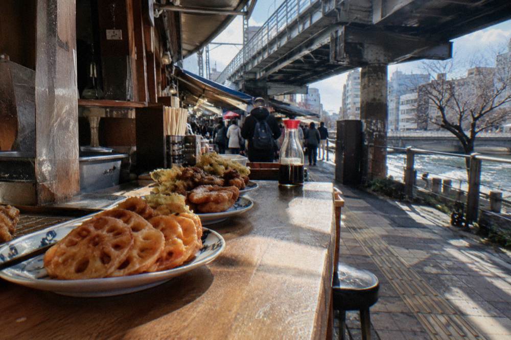 Small plates of Japanese street food laid out along a wooden counter