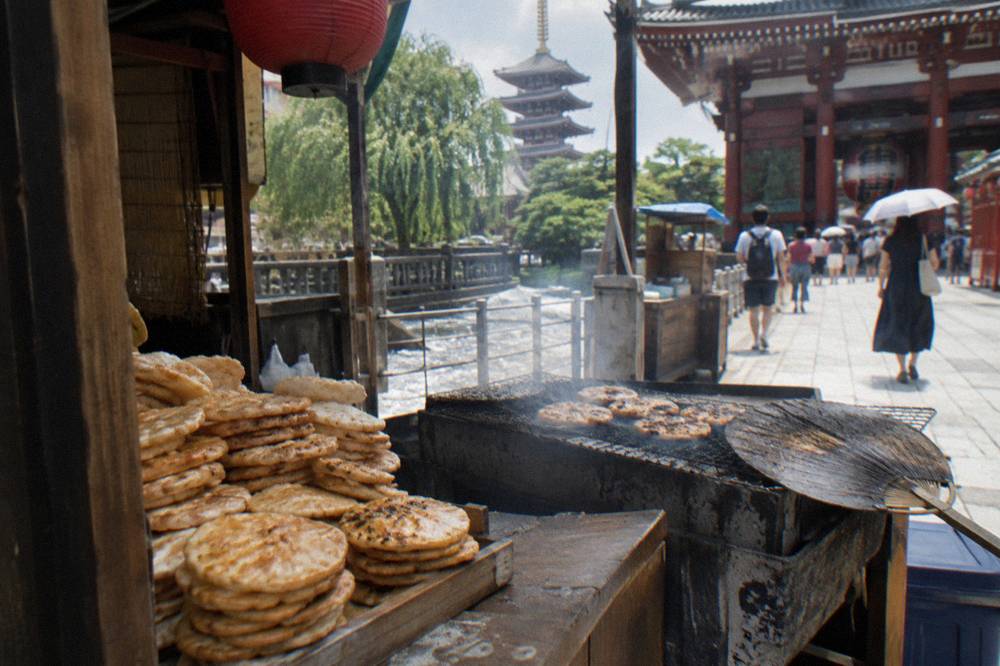 Close view of a stall counter with stacked rice crackers and steaming grill in Asakusa