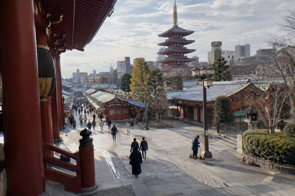 Wide view of the Senso-ji temple approach with a pagoda rising above shop rooftops